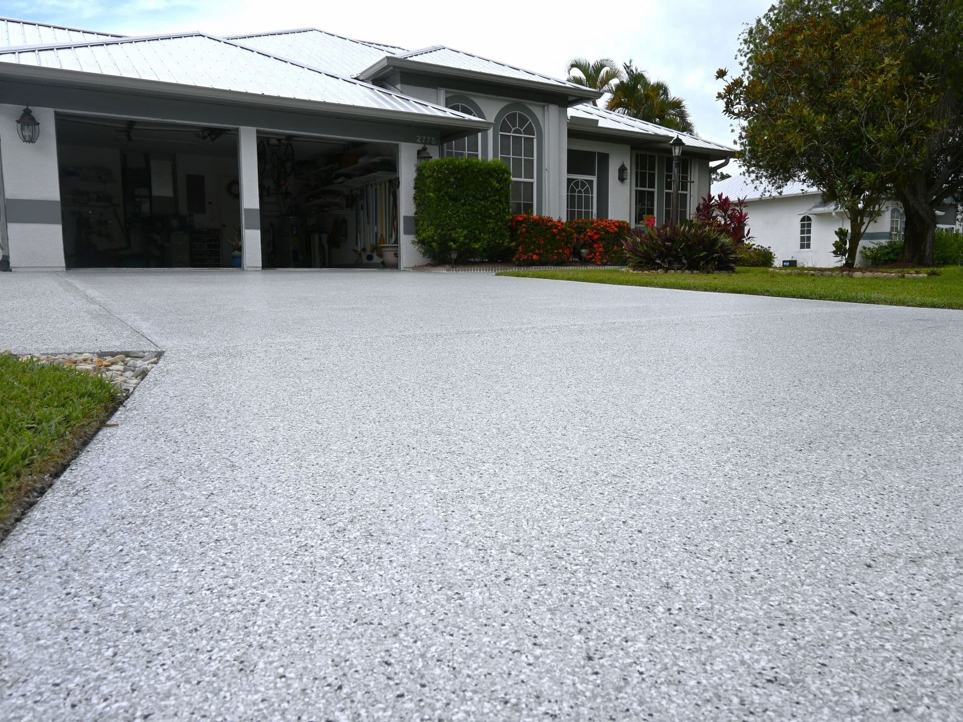 A beautifully finished driveway and open garage showcasing UV-resistant polyaspartic concrete coating.