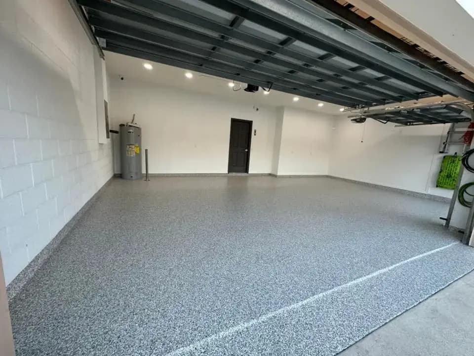 A bright, empty Fort Myers garage featuring a high-gloss gray decorative flake floor coating that extends up the stem walls.