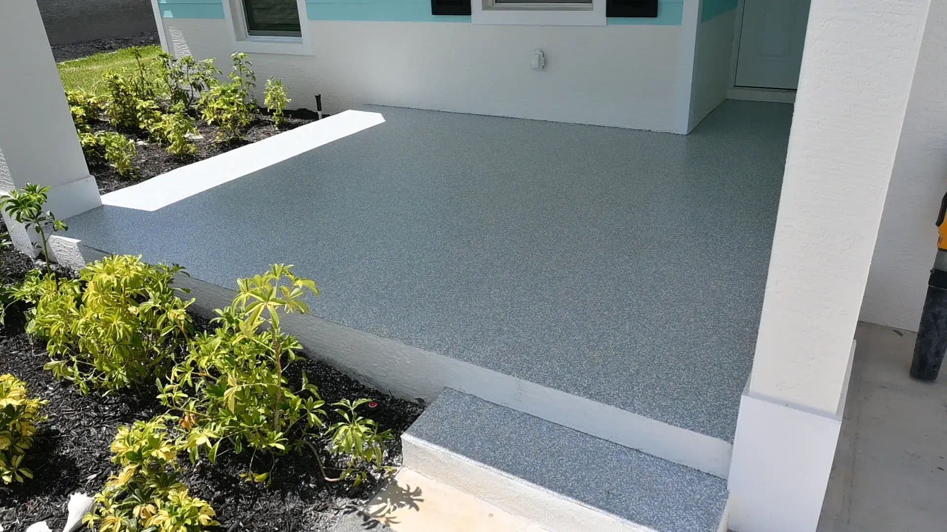 A low-maintenance patio coating with a gray flake finish on a Florida front porch