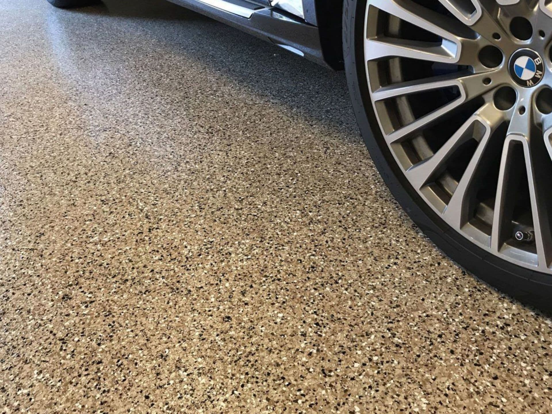 A spotless polyaspartic garage floor with a tan and black decorative flake finish